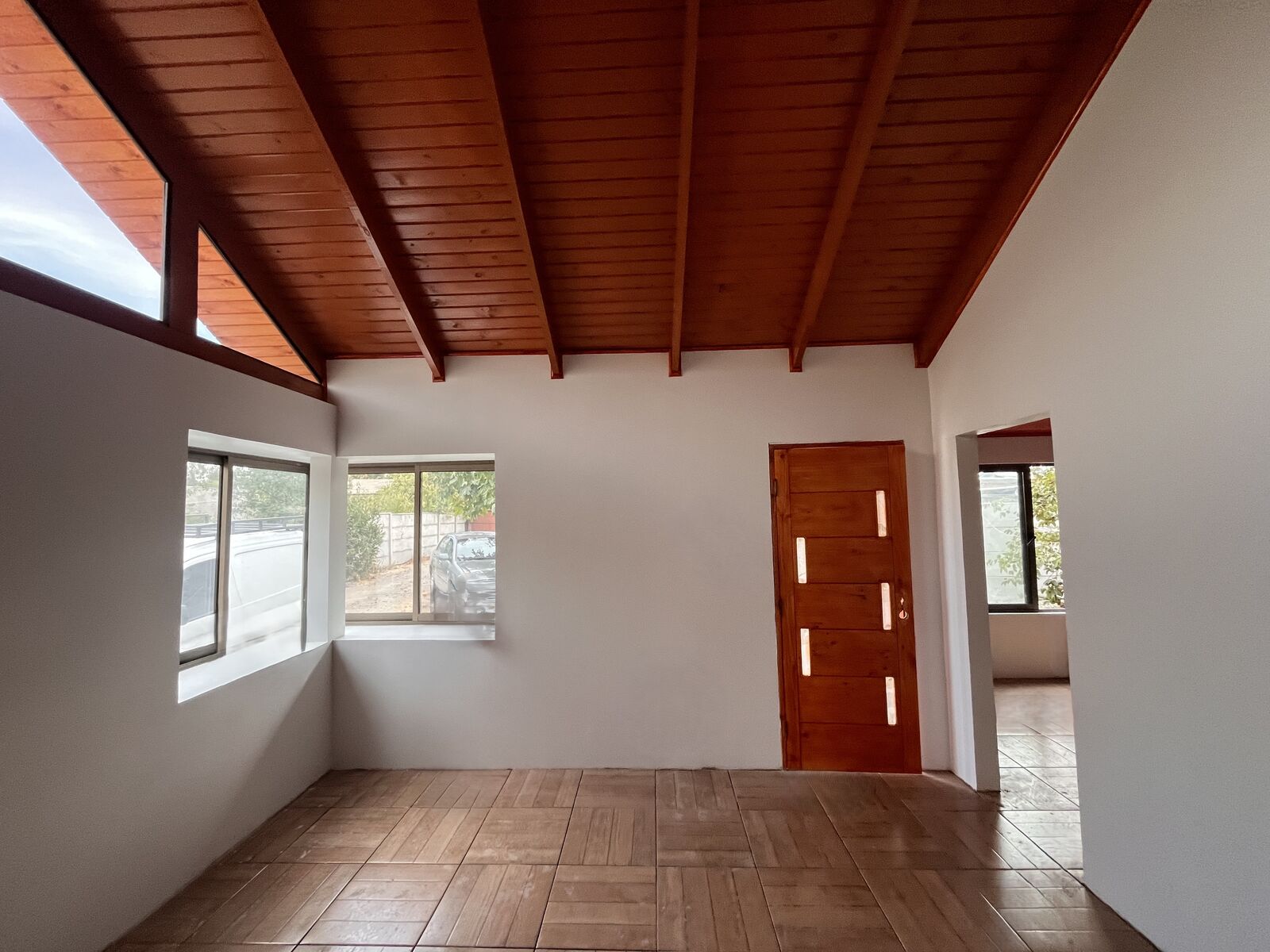Living-comedor de doble altura con cielo machihembrado en vivienda de 97 m² construida por GHM Civil en Talca