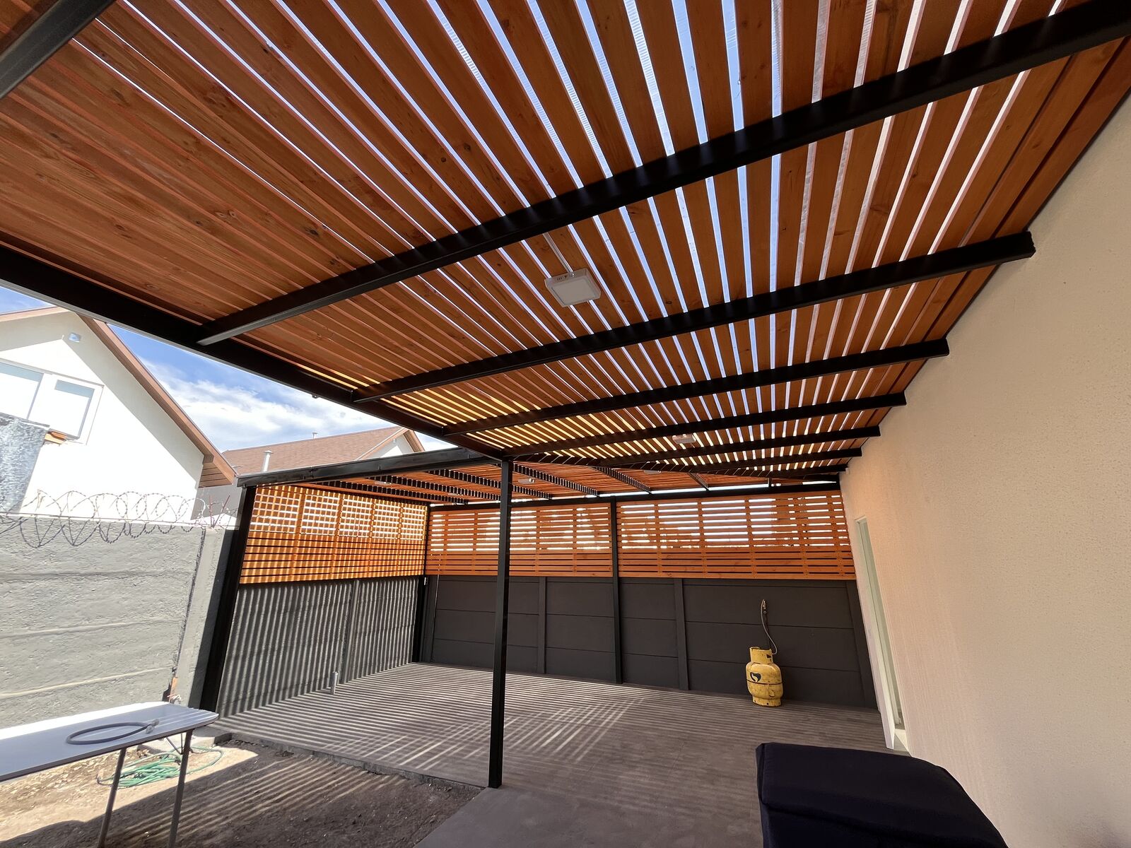 Terraza cubierta con estructura metálica y listones de madera ejecutada por GHM Civil en Talca